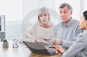 Focused mature couple talking to financial advisor at home