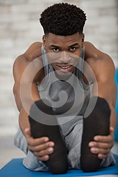 focused mid adult man stretching leg while practicing yoga photo