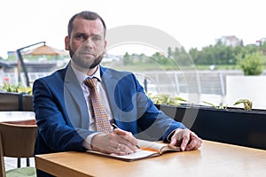 Focused middle aged 40s businessman writes notes in a personal diary, plans a working day, checks a schedule
