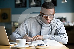 Focused millennial african student making notes while studying i