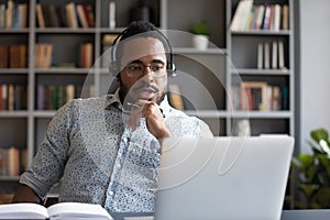 Focused millennial mixed race guy consulting clients online.