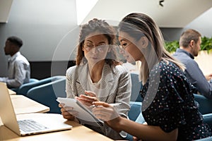 Focused millennial women discuss business plan in office