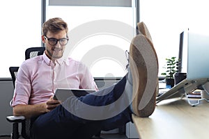 Focused modern businessman working with digital tablet in his modern office, legs on desk