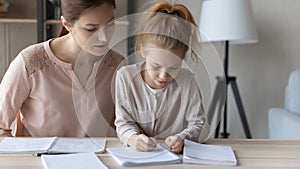 Focused mom help junior school age daughter to do homework