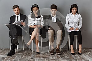 focused multiethnic business people with digital devices and folders waiting