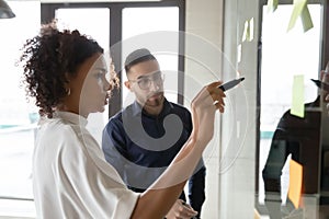 Focused multiethnic colleagues develop business plan on glass wall