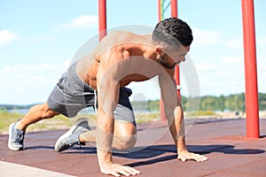 Focused muscular guy doing plank exercise outdoors