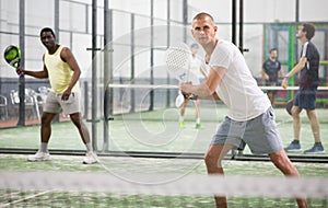 Focused padel player hitting two handed backhand in close court