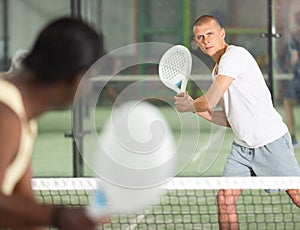 Focused padel player hitting two handed backhand in close court