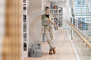 Focused pensive mature woman bookworm reading book in library. Lifelong learning