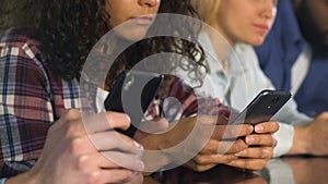 Focused people watching football game in bar, checking bets on smartphone