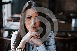 Focused photo. Businesswoman in official clothes is indoors in cafe at daytime