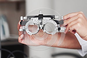 Focused photo. Female hands holding the optical device for eye testing