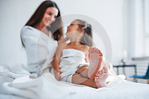 Focused photo. Young mother with her daugher have beauty day indoors in white room