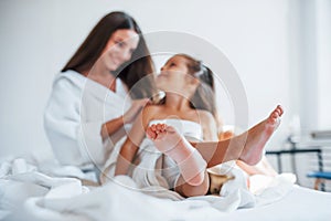 Focused photo. Young mother with her daugher have beauty day indoors in white room