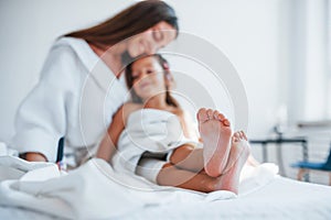 Focused photo. Young mother with her daugher have beauty day indoors in white room