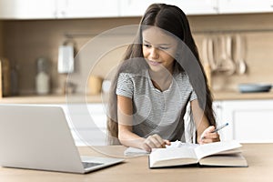 Focused positive schoolkid studying at home, watching online lesson photo
