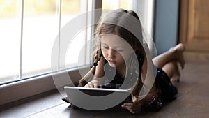 Focused pre teen school kid doing home task online