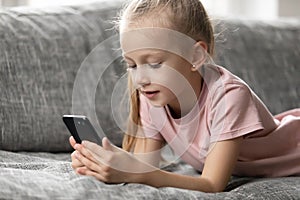 Focused preschooler child girl resting on sofa at home