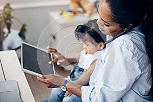 Focused and productive. a young mother caring for her baby girl while working from home.