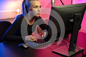 Focused Professional E-sport Gamer Girl with Headset Playing Online Video Game on PC photo