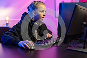 Focused Professional E-sport Gamer Girl in Hoody Playing Online Video Game on PC