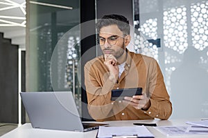 Focused professional analyzing data on laptop and tablet in modern office