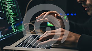 Focused programmer typing code on laptop in dark room