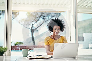 Focused on reaching her deadline. an attractive young woman working on her laptop at home.