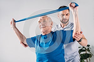 focused rehabilitation therapist assisting senior man