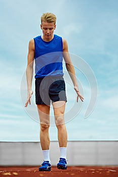 Focused runner propelling forward with intent. Young athlete man, professional sportsman warming-up before championship.