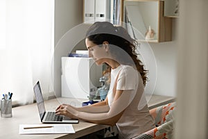 Focused 35s woman sit at desk working online using laptop photo