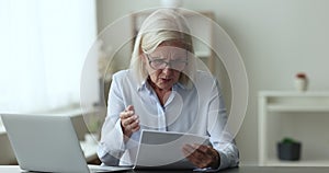 Focused senior business professional woman reviewing paper document