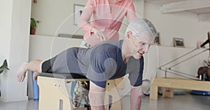Focused senior caucasian man exercising with female pilates coach, unaltered, in slow motion
