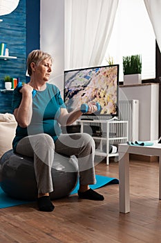 Focused senior man holding dumbbells working muscles exercise streching body