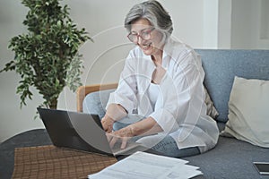Focused senior woman using computer for research and creative work