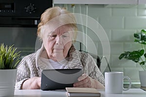 Focused senior woman with digital tablet at home looking for information