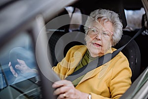 Focused senior woman driving car alone, enjoying car ride. Safe driving for elderly adults, older driver safety.