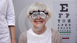 Focused senior woman in phoropter on vision examination, health check, test