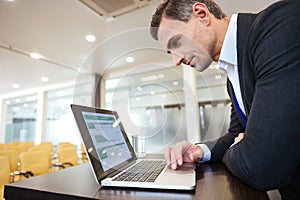 Focused serious business man working with laptop in conference hall