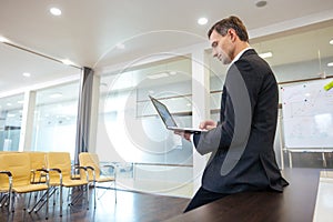 Focused serious businessman preparing for presentation using laptop