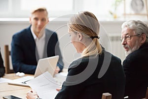 Focused serious businesswoman reading document at group meeting