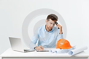 Focused serious hardworking engineer busy working on big architectural project late, sitting at his workspace using