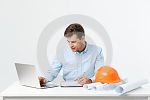 Focused serious hardworking engineer busy working on big architectural project late, sitting at his workspace using