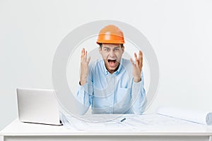 Focused serious hardworking engineer busy working on big architectural project late, sitting at his workspace using