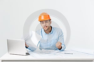 Focused serious hardworking engineer busy working on big architectural project late, sitting at his workspace using