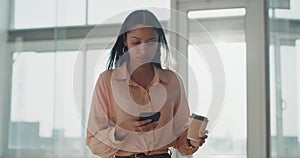 Focused, serious and powerful business woman using a phone and walking in the corridor or office building. Young