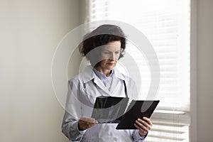 Focused serious senior doctor woman examining xray radiography images