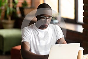 Focused black millennial guy working on computer photo