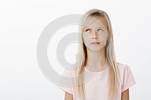 Focused serious young kid recalling learned material while answering near blackboard at school. Studio shot of concerned